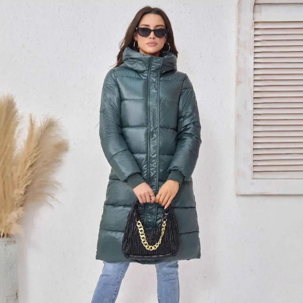 Frau mit modischer, langer, dunkelgrüner Daunenjacke mit Kapuze und schwarzer Tasche, IsabellBoutique030
