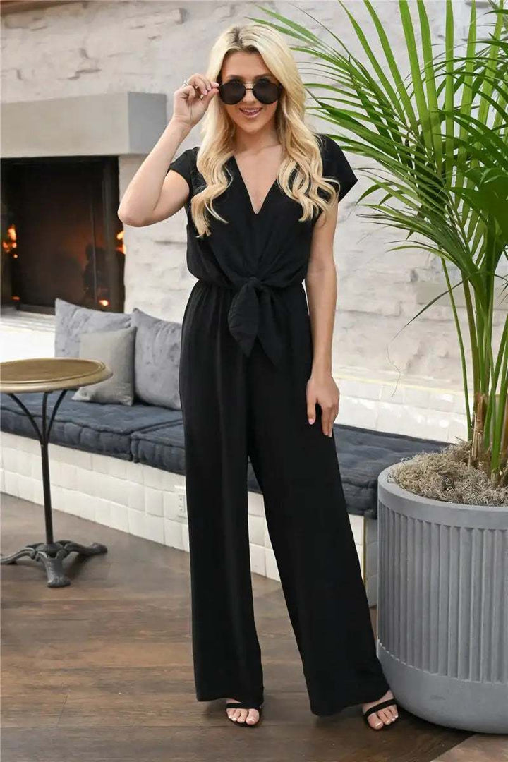 Schwarzer, ärmelloser Jumpsuit mit V-Ausschnitt und Schleife in der Taille, weite Hosenbeine. IsabellBoutique030