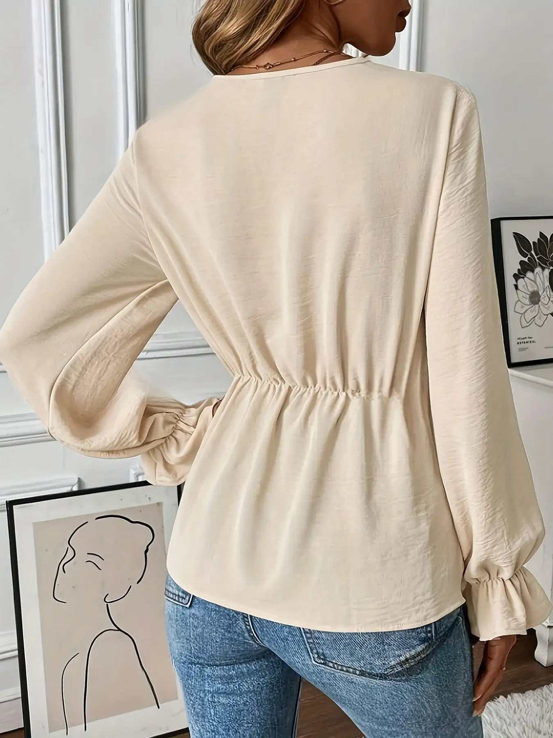 Cremefarbene Damenbluse mit Gummizug in der Taille, langen Puffärmeln und Rüschenbündchen, kombiniert mit blauer Jeans. IsabellBoutique030