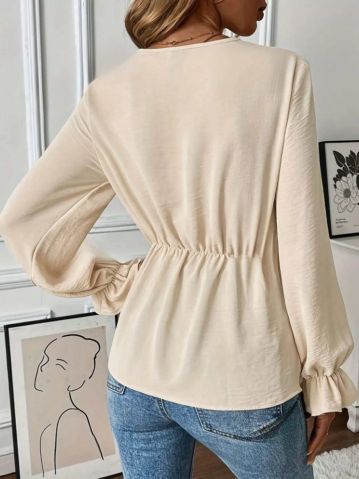 Cremefarbene Damenbluse mit Gummizug in der Taille, langen Puffärmeln und Rüschenbündchen, kombiniert mit blauer Jeans. IsabellBoutique030