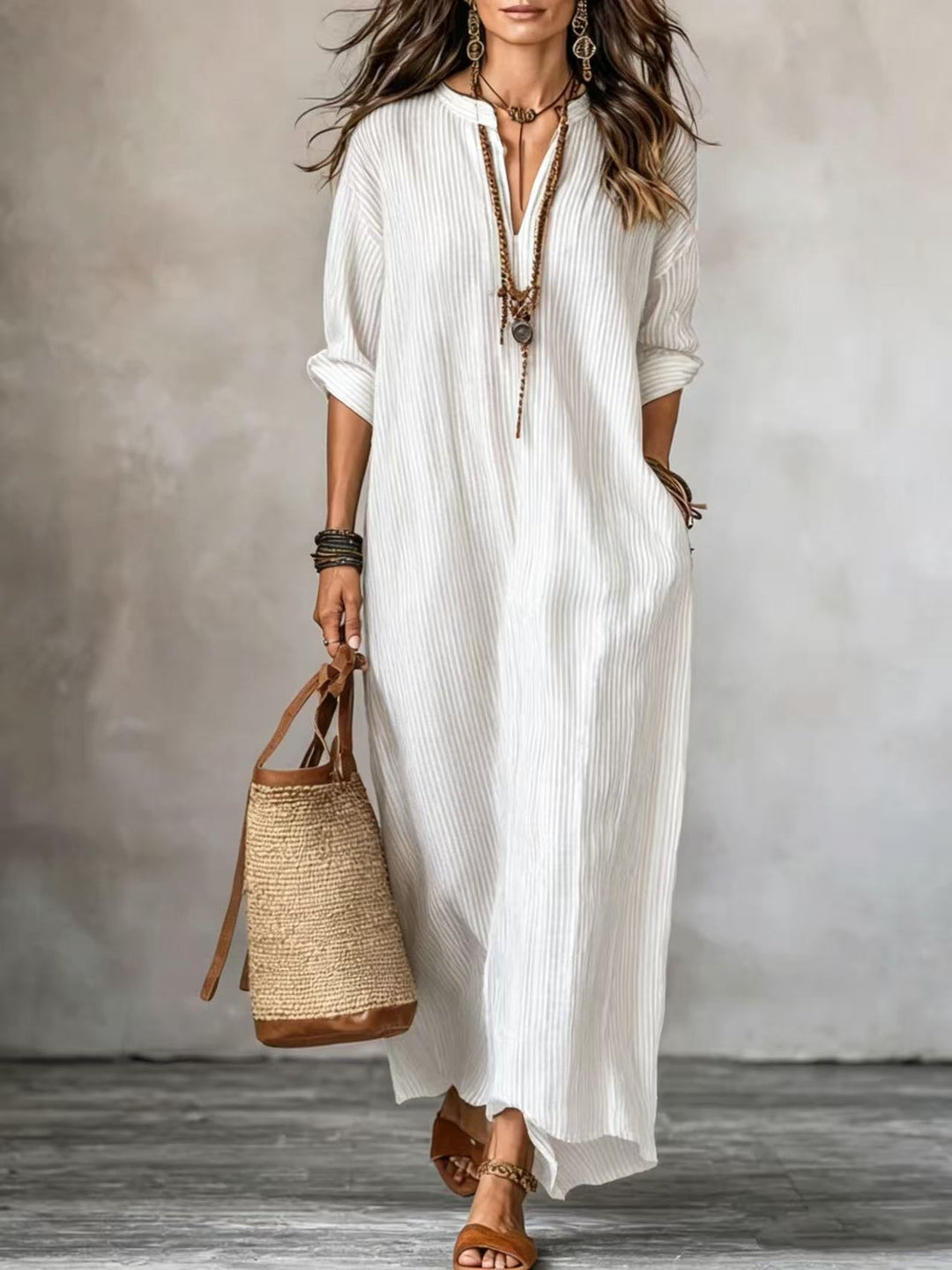 Gestreiftes Maxikleid in Weiß mit V-Ausschnitt und weiten Ärmeln, kombiniert mit Basttasche. IsabellBoutique030