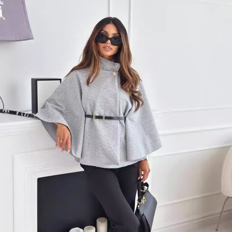 Grauer Poncho mit Stehkragen, Gürtel und weiten Ärmeln, kombiniert mit schwarzer Hose und Tasche. IsabellBoutique030