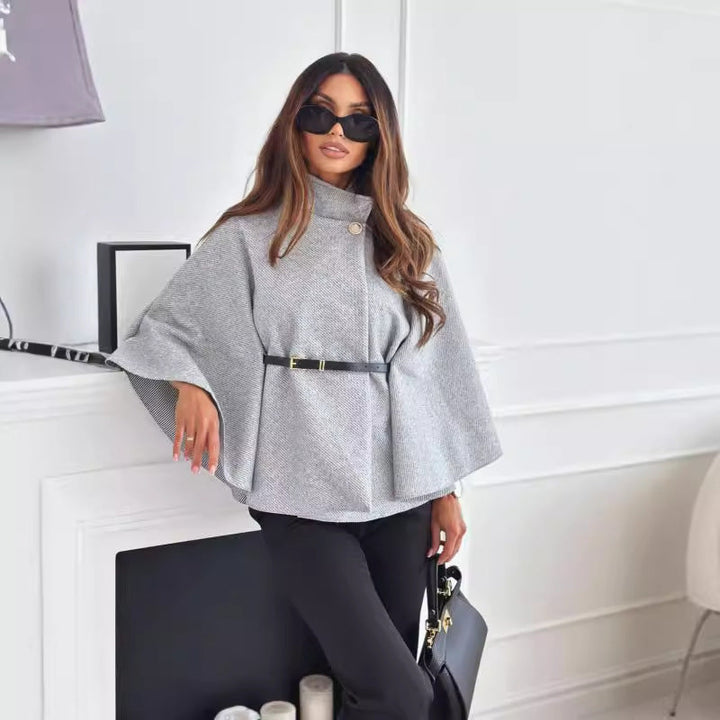 Grauer Poncho mit Stehkragen, Gürtel und weiten Ärmeln, kombiniert mit schwarzer Hose und Tasche. IsabellBoutique030