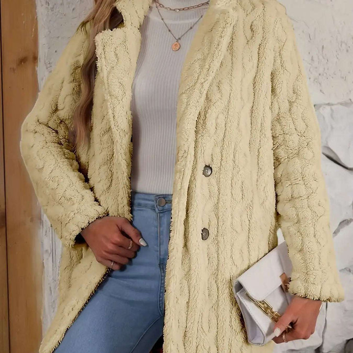 Beiger Teddy-Mantel mit durchgehendem Zopfmuster, Kragen und zwei Knöpfen, kombiniert mit weißem Rollkragenpullover und Jeans. Hält eine weiße Clutch. IsabellBoutique030.