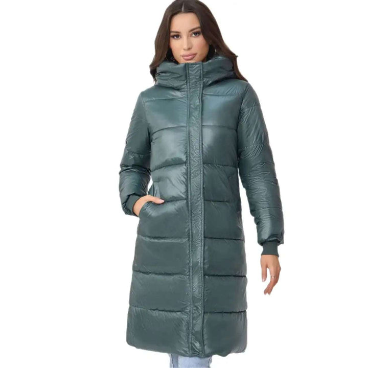 Lange, wattierte Steppjacke in Petrolgrün mit Kapuze für Damen. Glänzende Oberflächen und seitliche Eingrifftaschen. IsabellBoutique030