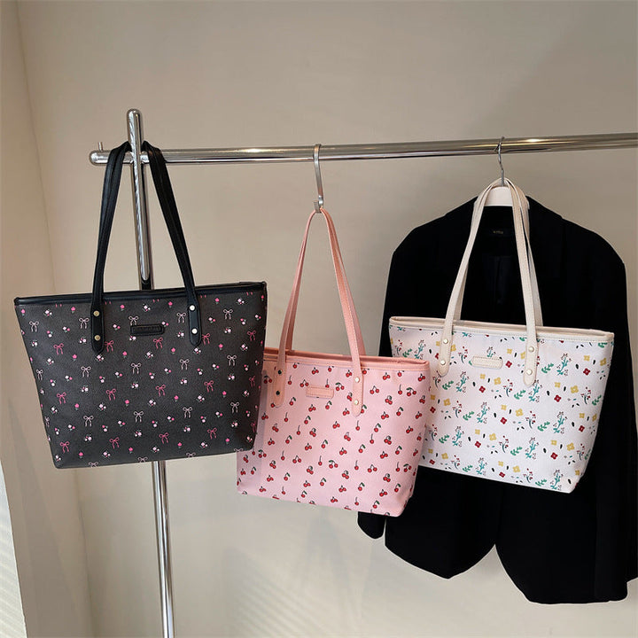 Drei Henkeltaschen mit süßen Mustern: schwarz mit Schleifen, rosa mit Kirschen und weiß mit Blumen. IsabellBoutique030