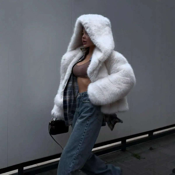 Weiße flauschige Kunstpelzjacke mit Kapuze, getragen über einem Crop-Top und Jeans. IsabellBoutique030