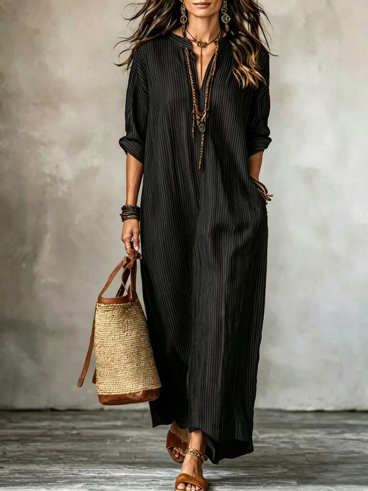 Schwarzes, gestreiftes Maxikleid mit V-Ausschnitt und langen Ärmeln, kombiniert mit Ledersandalen und einer Korbtasche. IsabellBoutique030