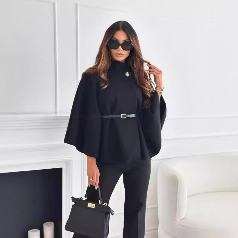 Moderne schwarze Cape-Bluse mit Stehkragen und schmalem Gürtel, kombiniert mit Hose und Handtasche. IsabellBoutique030