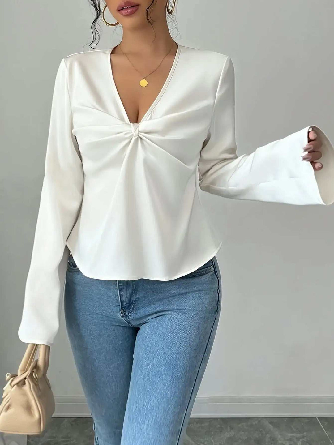 Weiße Damenbluse mit tiefem V-Ausschnitt und Knoten vorne, Glockenärmeln, kombiniert mit blauer Jeans. IsabellBoutique030