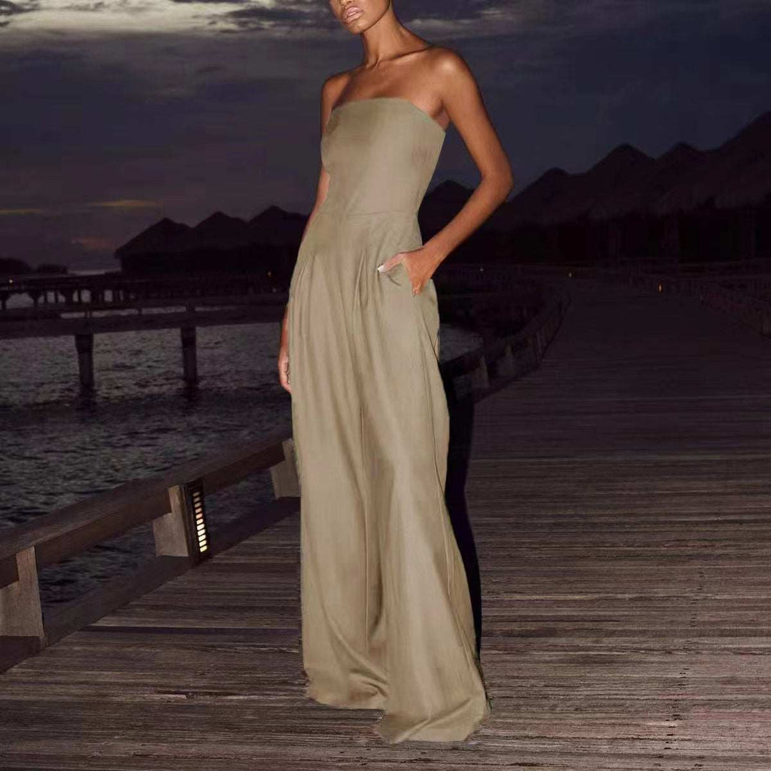 Bodenlanger, trägerloser Jumpsuit in Khaki mit weiten Beinen und Taschen. Steht auf einem Holzsteg bei Nacht. IsabellBoutique030