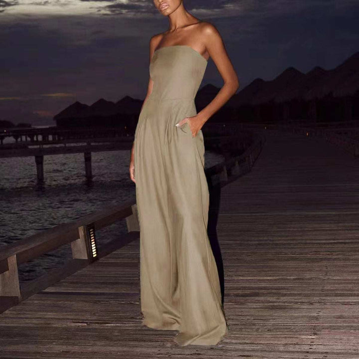Bodenlanger, trägerloser Jumpsuit in Khaki mit weiten Beinen und Taschen. Steht auf einem Holzsteg bei Nacht. IsabellBoutique030