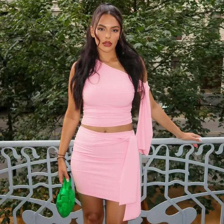 Eine Frau in einem rosa One-Shoulder-Crop-Top und Wickelrock mit Schärpe. IsabellBoutique030