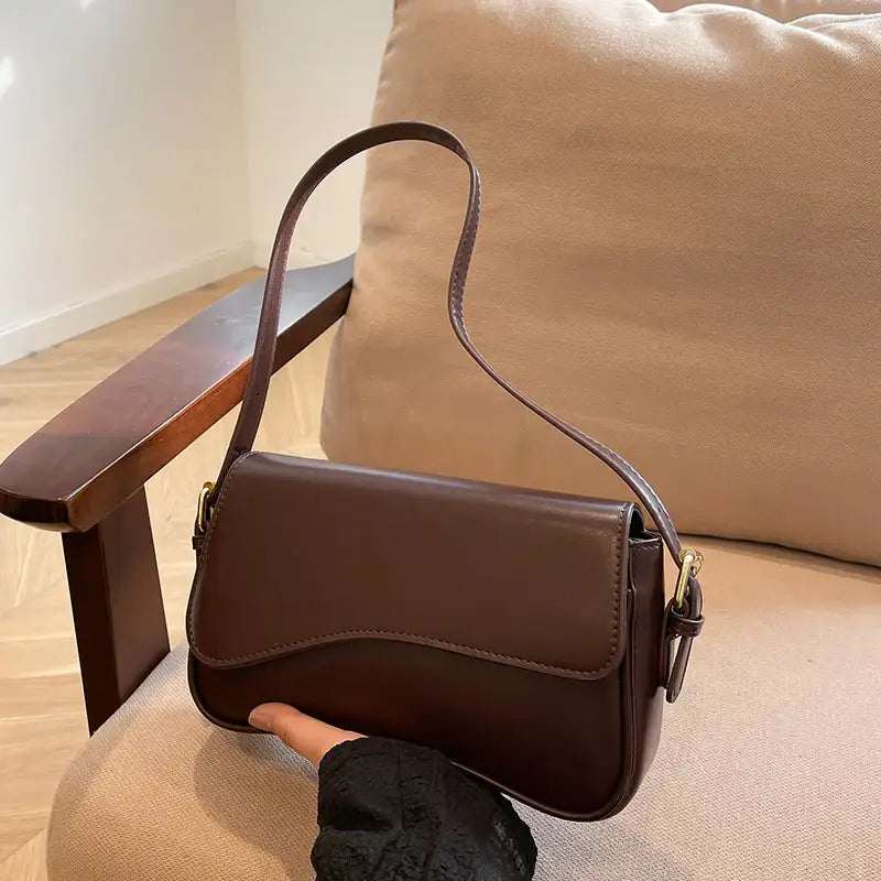 Dunkelbraune Schultertasche aus Leder mit geschwungener Klappe und goldenen Details, stilvoll und elegant. IsabellBoutique030